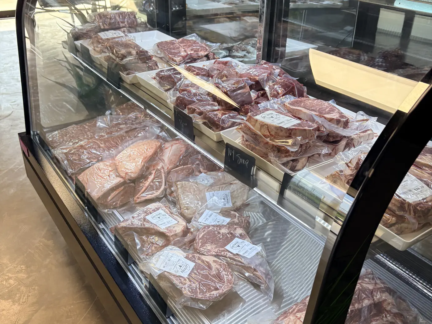 A glass meat case full of labeled cuts