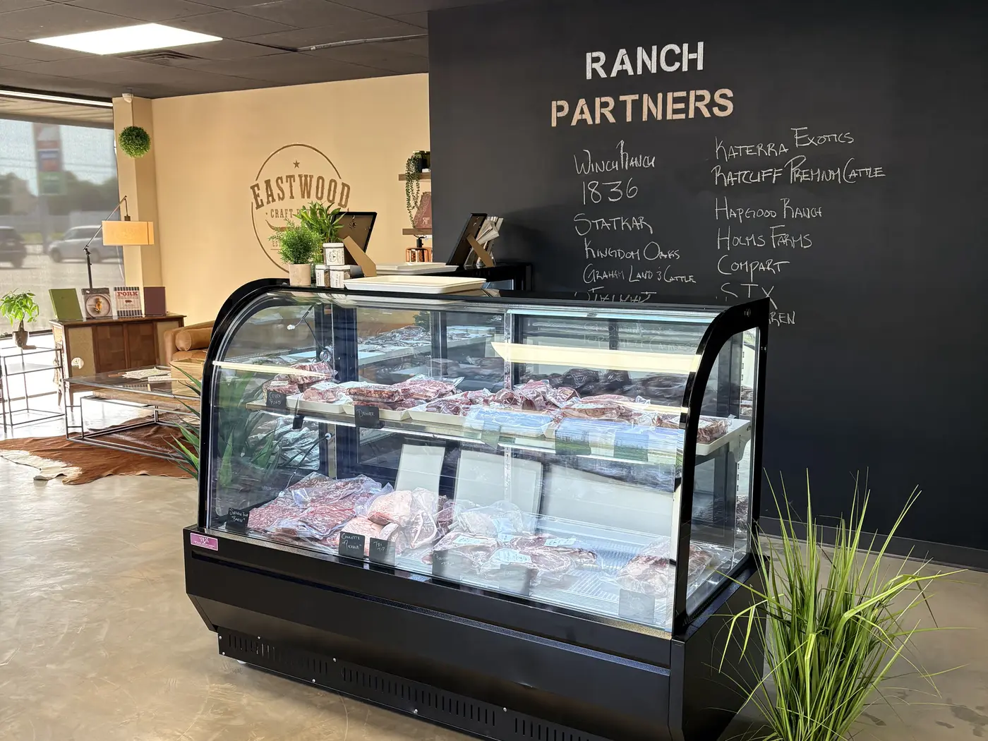 Meat case in front of a chalkboard wall listing the shop's ranch partners
